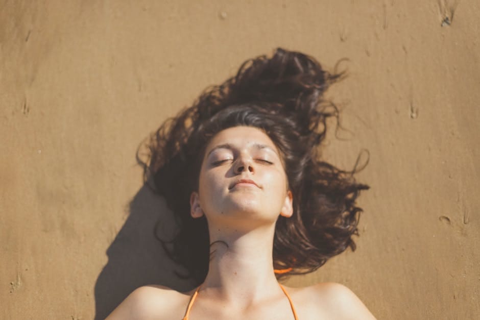 A serene portrait of a woman with closed eyes enjoying the sun on a sandy beach in Weligama, Sri Lanka.