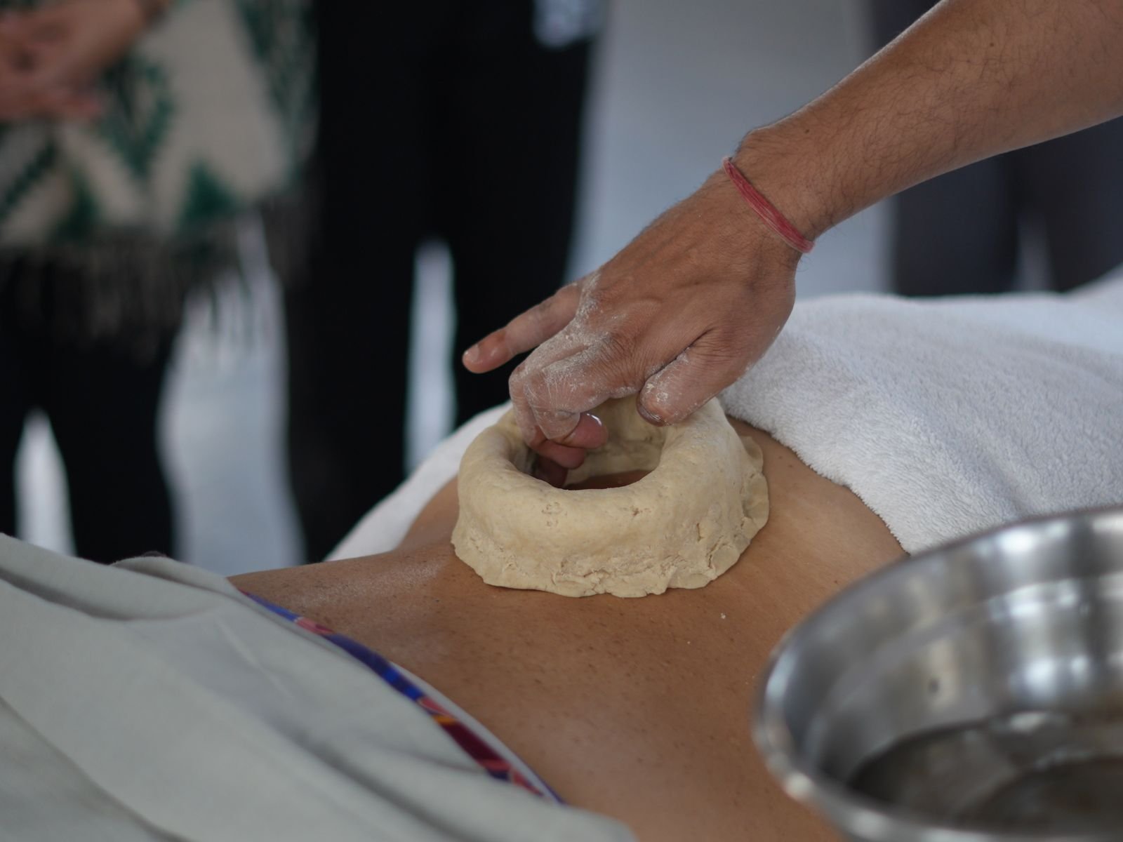 Therapist preparing a traditional Ayurvedic Kati Basti oil treatment