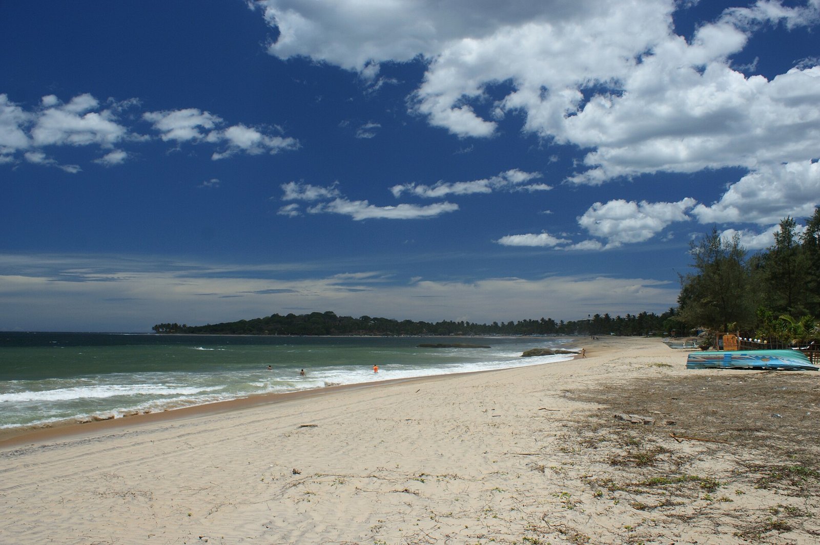 Long sandy beach at Arugam Bay under a blue sky