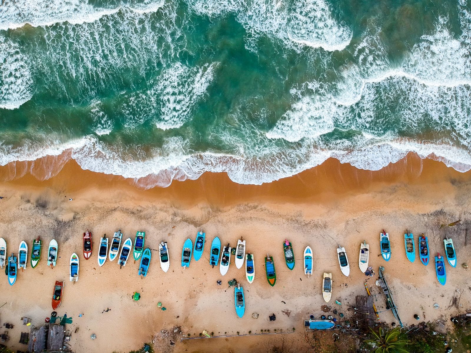 Fishing boats lined up on the sand at Arugam Bay from above
