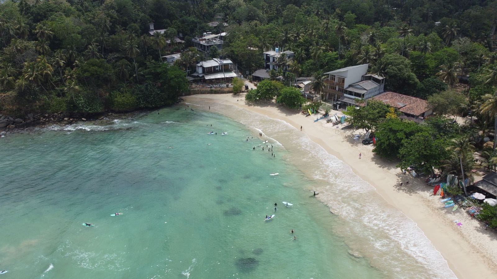 Aerial view of Hiriketiya Bay with surfers in turquoise water