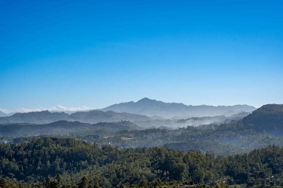 Stunning panoramic view of misty mountains in Sri Lanka under a clear blue sky.