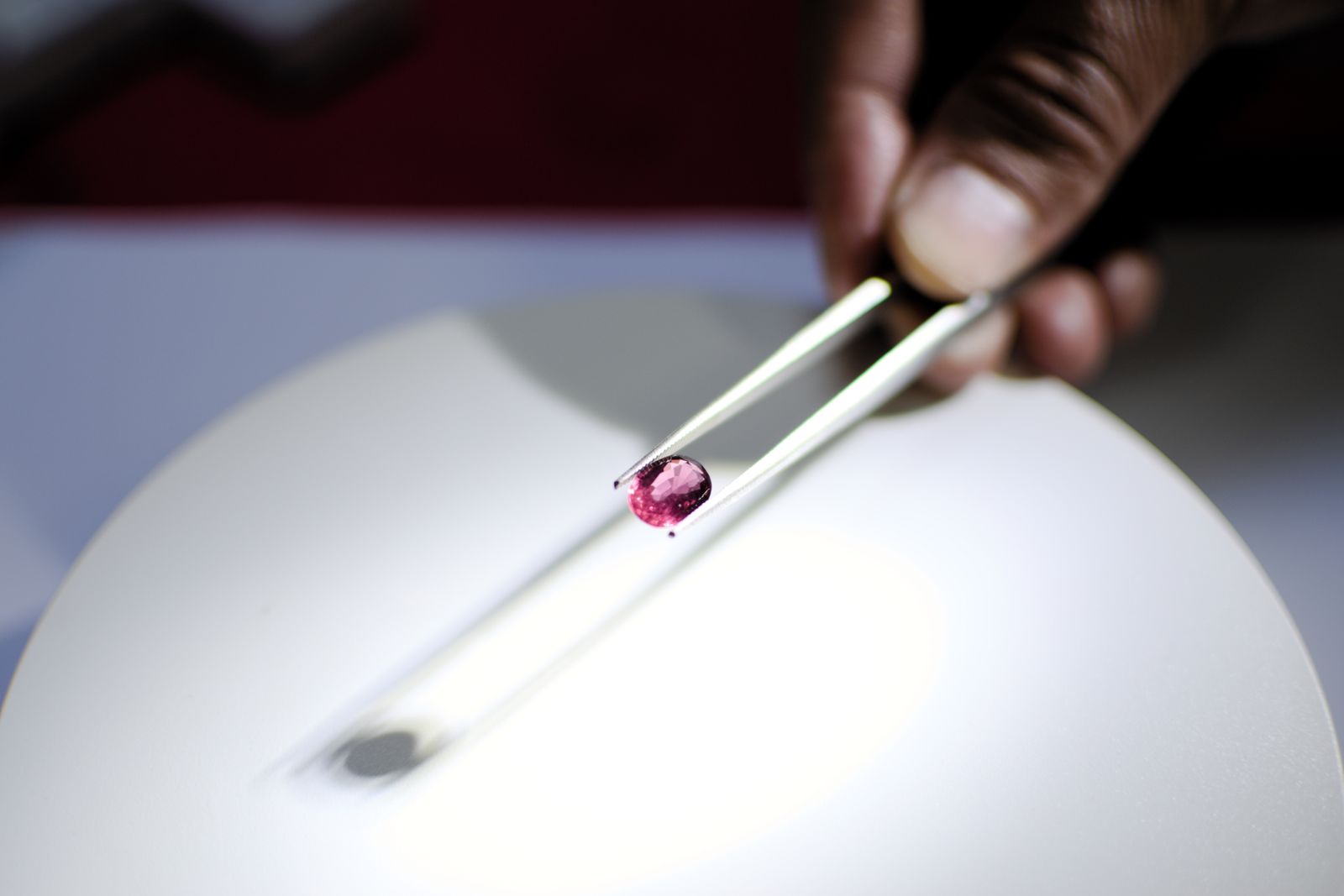 Hand holding a red gemstone with tweezers — Ratnapura's gem industry