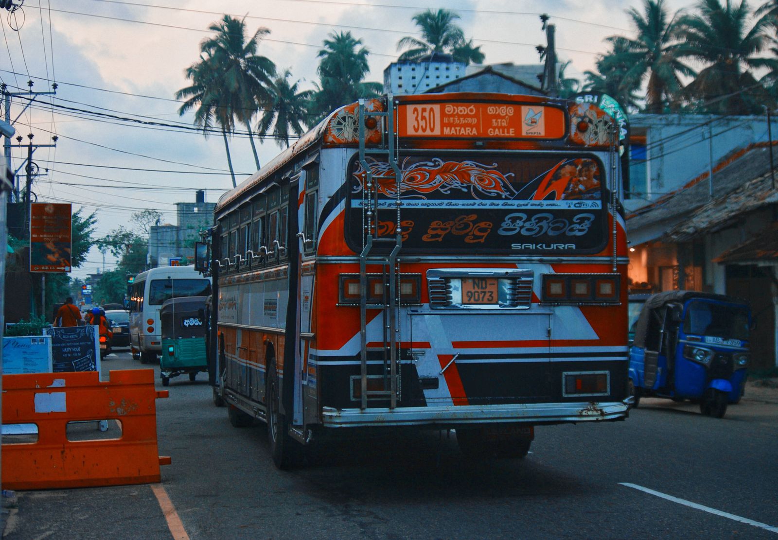 A vividly decorated bus on a busy Sri Lankan street at dusk
